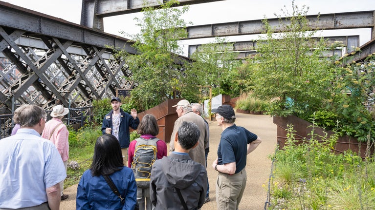 A tour guide giving a talk to a group of people on top of Castlefield Viaduct, Manchester